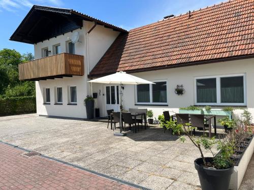 uma casa com um pátio com uma mesa e um guarda-chuva em Danner Familien-Ferienwohnungen Schörfling am Attersee em Schörfling