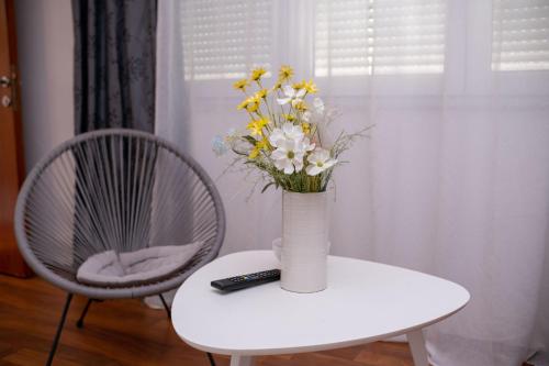 a vase of flowers on a table with a remote control at Apartment Mery in Mostar