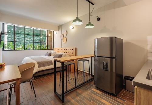 a kitchen with a refrigerator and a bedroom with a bed at The Somos Flats Laureles in Medellín