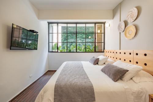 a white bedroom with a large bed and a window at The Somos Flats Laureles in Medellín