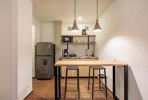 a kitchen with a counter with stools and a refrigerator at The Somos Flats Laureles in Medellín