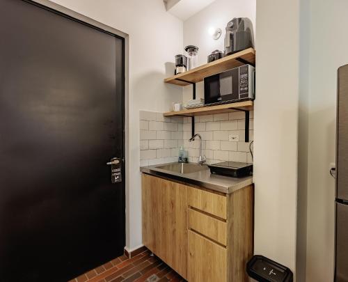 a small kitchen with a sink and a microwave at The Somos Flats Laureles in Medellín