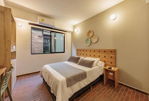 a bedroom with a bed and a window at The Somos Flats Laureles in Medellín