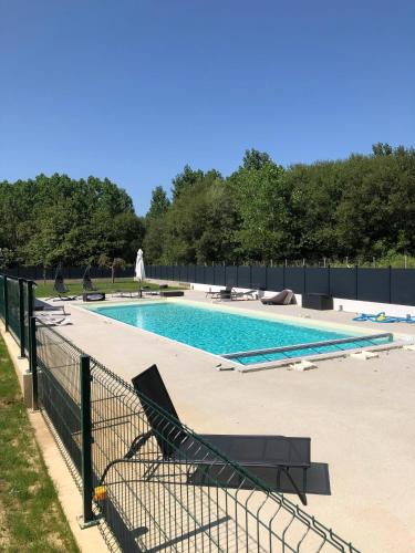 une piscine avec des chaises et une clôture dans l'établissement Le Montmieri, à Dax