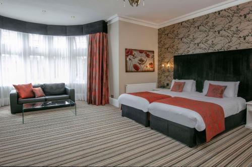 a hotel room with a large bed and a couch at Best Western Plus Burlington Hotel in Folkestone