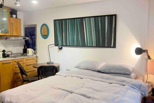 a bed in a room with a window and a kitchen at Studio in the best place of town! in Tel Aviv