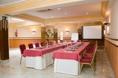 a conference room with tables and chairs and a screen at Hotel Del Val in Andújar
