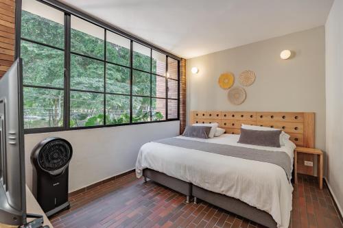 a bedroom with a bed and a large window at The Somos Flats Laureles in Medellín