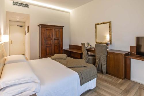 a bedroom with a bed and a desk and a mirror at Hotel Machiavelli Palace in Florence