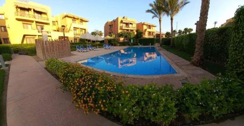 a swimming pool with chairs and trees and buildings at Luxury Chalet in Mountain View 2 , El-Sokhna with Sea View , Pool View and Garden View Families Only in Ain Sokhna