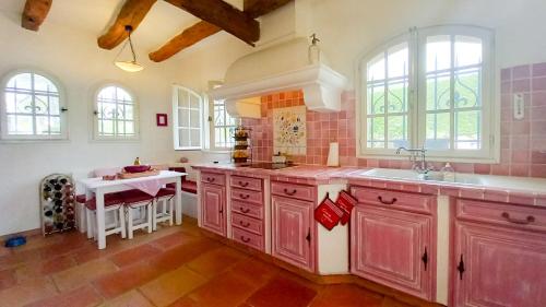 une cuisine avec des placards roses, un évier et une table dans l'établissement Villa Parc Saint-Martin, à Mougins