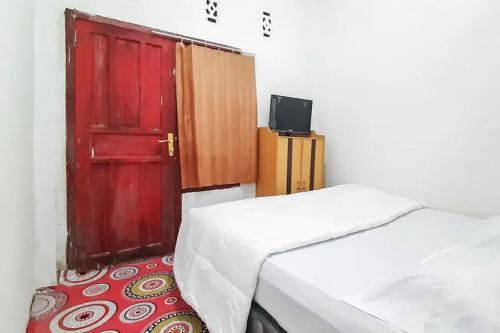 Camera con porta rossa, letto e TV di Homestay Cantika Koto Tengah RedPartner a Sungaipenuh