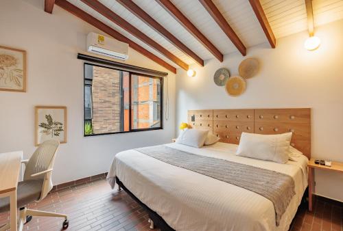 a bedroom with a bed and a desk and a window at The Somos Flats Laureles in Medellín