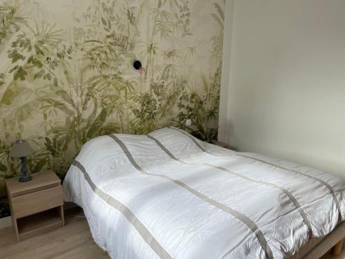 Ce lit se trouve dans une chambre dotée d'un mur orné de plantes. dans l'établissement Maison 12 pers, Proche plages, Le Pouldu, à Clohars-Carnoët