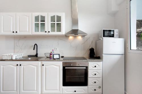 a white kitchen with a sink and a refrigerator at Babosas Charm in Funchal