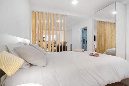 een witte slaapkamer met een groot wit bed met kussens bij Babosas Charm in Funchal