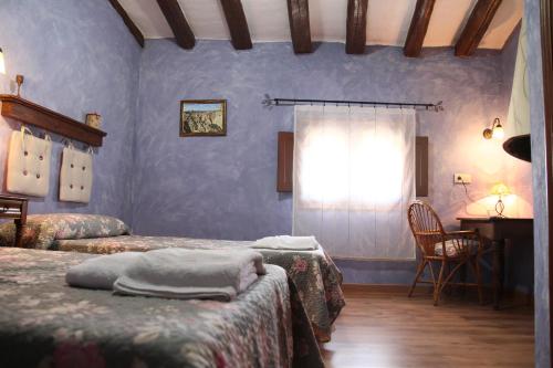 a bedroom with two beds and a table and a window at Agroturismo "La Bardena Blanca II" in Arguedas