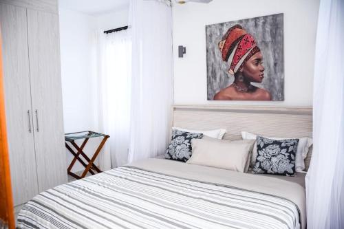 1 dormitorio con 1 cama con una pintura en la pared en Awali Villa B9, en Kilifi