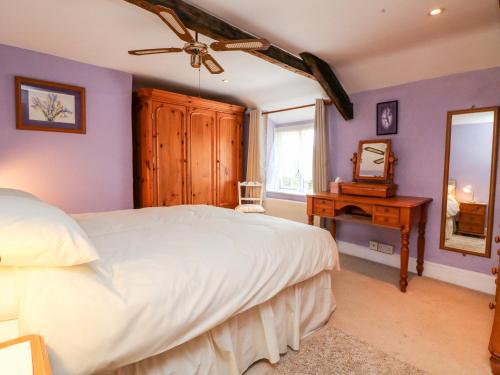 Un dormitorio con una cama blanca y un espejo. en The Old Forge Cottage, en Bude