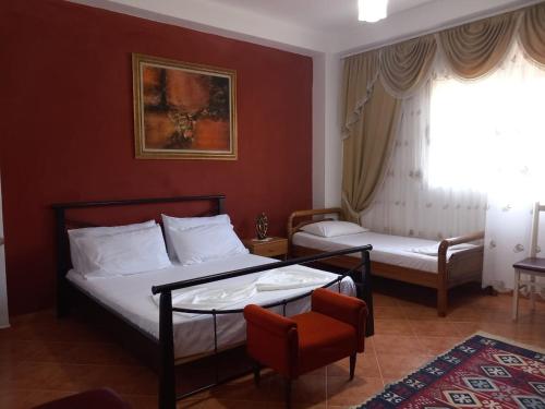 una habitación de hotel con 2 camas y una silla en Vila Gjoka en Himare