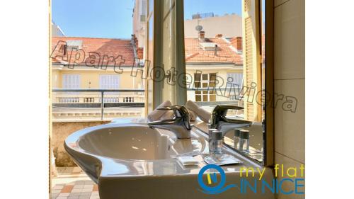 La salle de bains est pourvue d'un lavabo et d'une fenêtre avec vue. dans l'établissement ApartHotel Riviera - Grimaldi - Carre d'Or - Bigger 1 bedroom apartement AC - Balcony - 5mn Promenade des Anglais - BALCON PALAIS ALPHONSE KARR 1, à Nice