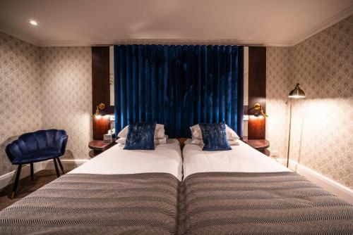 a bedroom with a large bed and a blue curtain at The Winchester Hotel and Spa in Winchester