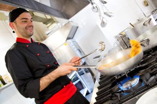 a man in a kitchen preparing food in a wok at Agriturismo San Galgano in Chiusdino