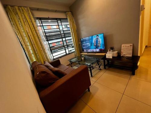 ein Wohnzimmer mit einem Sofa und einem TV in der Unterkunft 3BR Near KKIA Homestay Cyber City Apartment in Kota Kinabalu