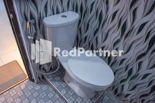 a white toilet in a bathroom with a wall at Hotel Rai's Palopo Exclusive Mitra RedDoorz in Palopo