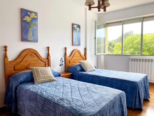 2 camas en un dormitorio con edredones azules en Apartamento Venecia en Unquera