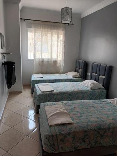 a room with three beds and a window at appartement de nouri à marti in Martil