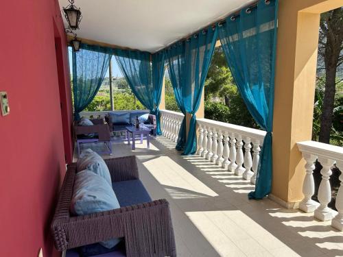 a balcony with blue drapes and a couch at Villa Selini in Kallithea