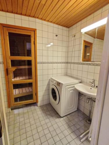 uma casa de banho com uma máquina de lavar roupa e um lavatório em Kotimaailma - Avara kolmio saunalla ja meri näkymällä, lähellä Helsingin keskustaa em Helsinque