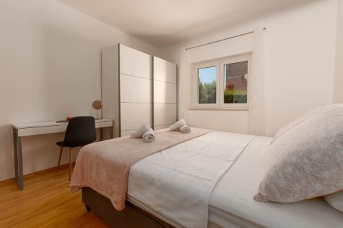 - une chambre blanche avec un grand lit et un bureau dans l'établissement Apartment Lucija, Stinjan, à Pula