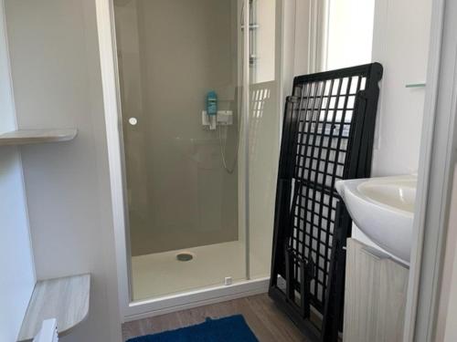 W łazience znajduje się szklana kabina prysznicowa i umywalka. w obiekcie Mobil-home (Clim, Tv)- Camping Narbonne-Plage 4* - 022 w mieście Narbonne-Plage