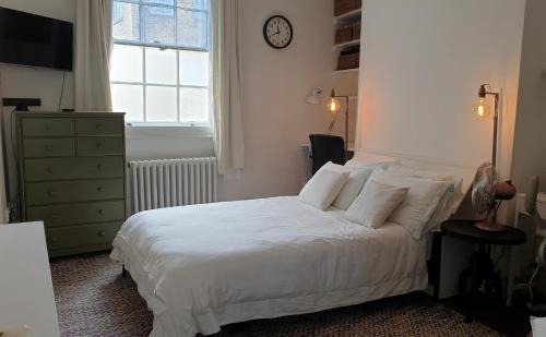 a bedroom with a white bed with a clock on the wall at Charming 1-Wall Bed Comfortable Studio in NWLondon in London
