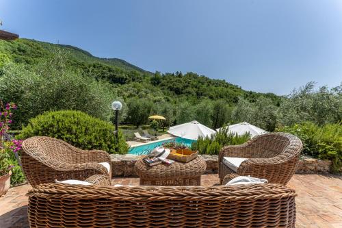 eine Terrasse mit Korbstühlen und einem Tisch neben einem Pool in der Unterkunft Fienile di Fabio in Vaiano