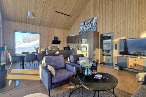 a living room with a couch and a tv and a table at Panorama Hovden - New Cabin With Amazing Views in Hovden