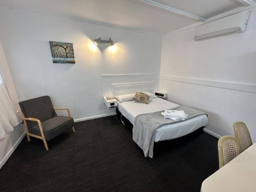 a small room with a bed and a chair at Charlton Motel in Charlton