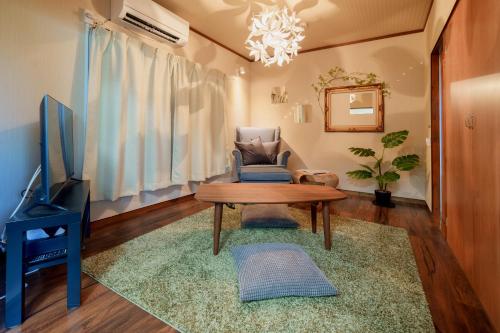 a living room with a table and a chair and a tv at R-house 2nd in Higashi-kanagawachō