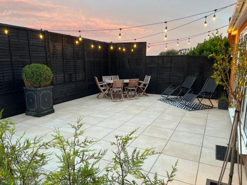 a patio with chairs and a table and lights at *BRAND NEW* Luxury Country Lodge in Burnham-on-Crouch