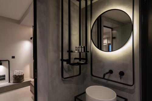 a bathroom with a round mirror and a toilet at Apikia Santorini in Pirgos