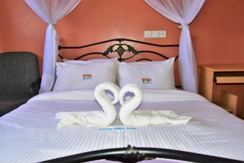 two white swans are sitting on a bed at Wagon Wheel Hotel Eldoret in Eldoret