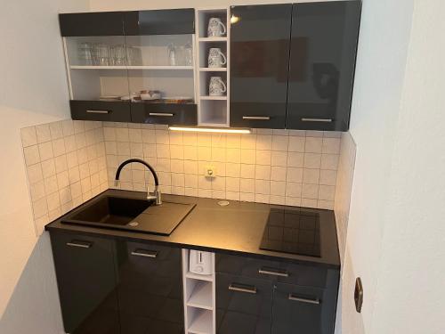 - une cuisine avec des placards noirs et un évier dans l'établissement Ferienwohnung Blankenstein, à Hattingen