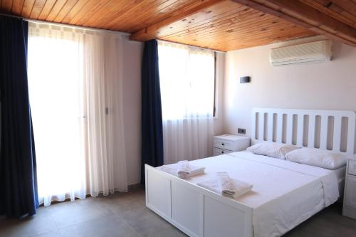 a bedroom with a white bed and large windows at La Sorella in Dalyan