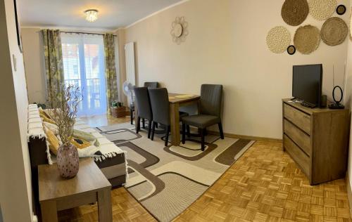 a living room with a table and chairs and a television at Apartament Omega I in Giżycko