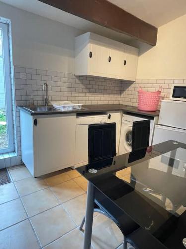 - une cuisine avec des appareils électroménagers blancs et une table dans l'établissement Le Petit Fleur - the little flower, cosy cottage, à Saint-Michel-de-Montjoie