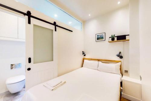 - une petite chambre avec un lit et des toilettes dans l'établissement Beautiful 1 bedroom apartment in Shepards Bush, à Londres