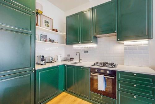- une cuisine verte et blanche avec des armoires vertes dans l'établissement Beautiful 1 bedroom apartment in Shepards Bush, à Londres