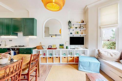 une cuisine avec des placards verts et une table avec des chaises dans l'établissement Beautiful 1 bedroom apartment in Shepards Bush, à Londres